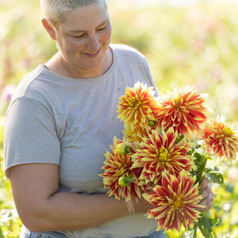 
                  
                    emily from grounded flower farm holding bunch of dahlias
                  
                